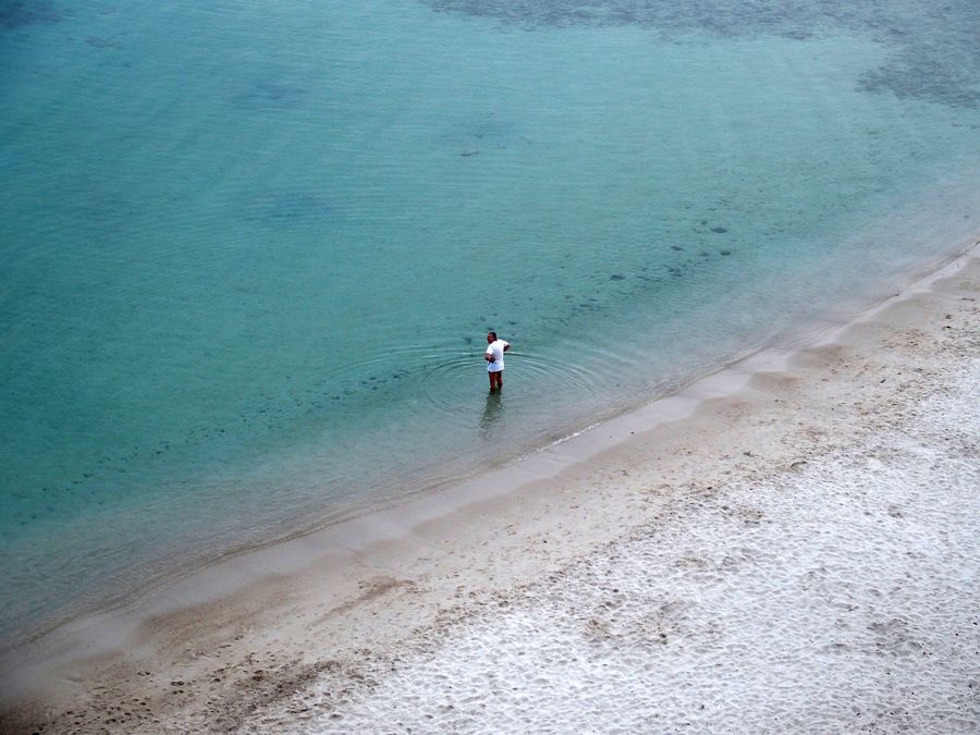 Un homme en tee-shirt rentre dans l'eau, plage de la Batterie à Marseille.