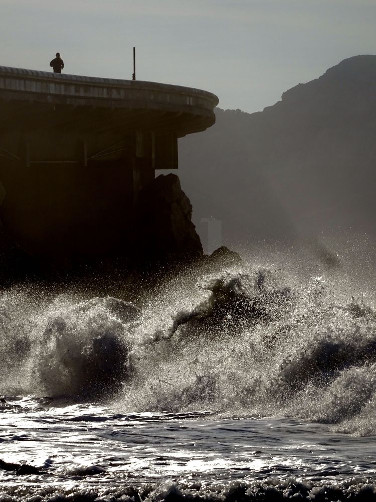 Un homme fait son footing sur la Corniche, au-dessus de la mer déchaînée. Une vague semble se transformer en cheval.