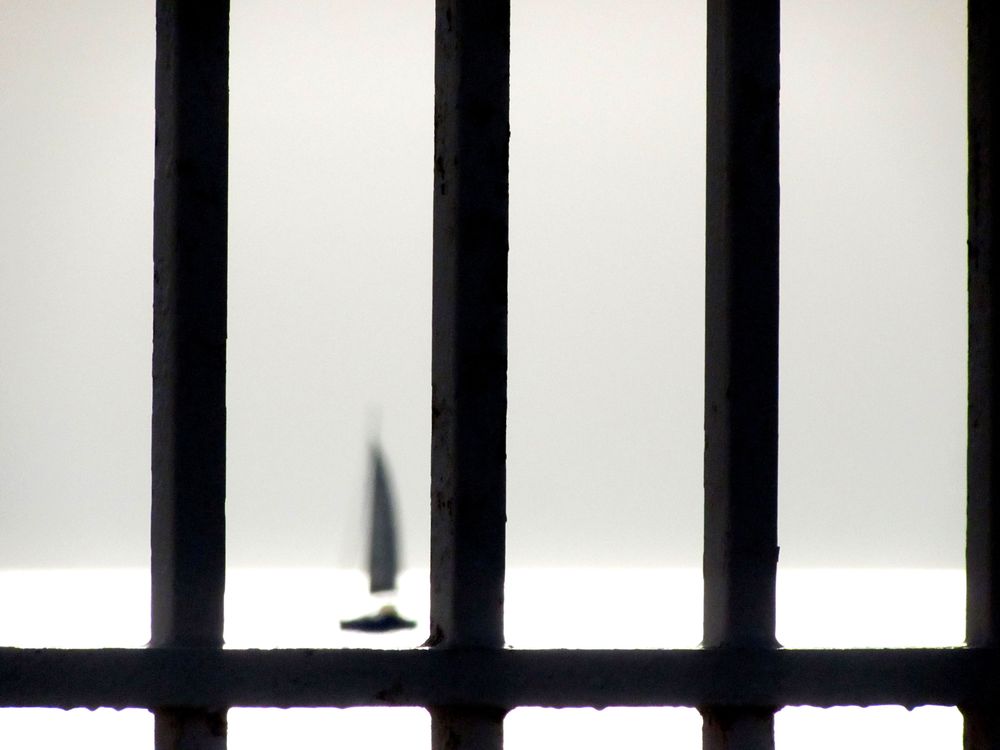 Un voilier apparaît à l'entrée du Vieux-Port de Marseille, derrière des grilles.