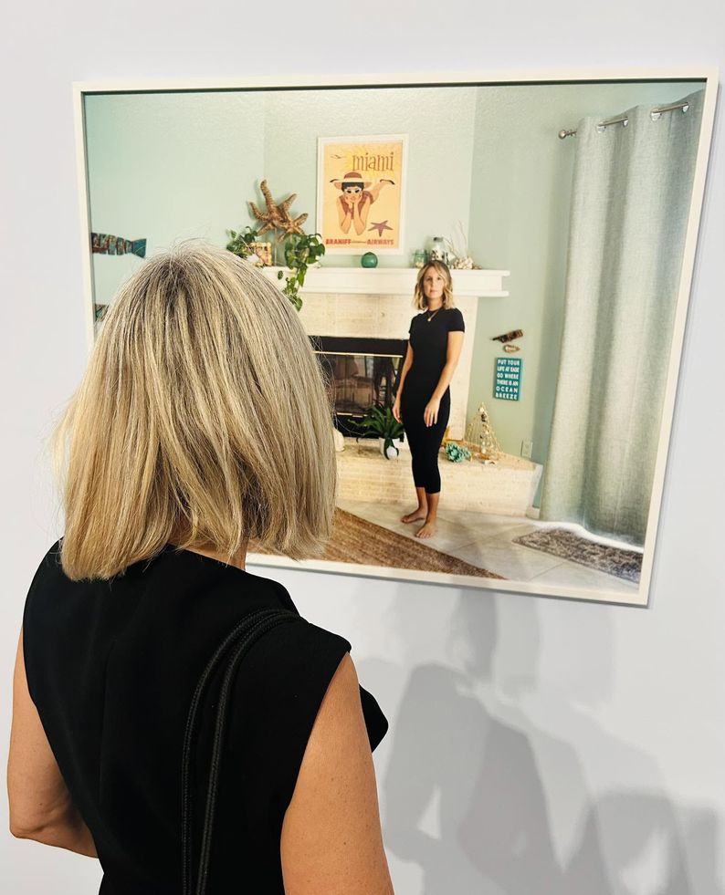 Une femme, habillée en noir, contemple une photo sur laquelle se trouve une femme, elle aussi, habillée en noir et qui semble projeter son regard sur le spectateur.