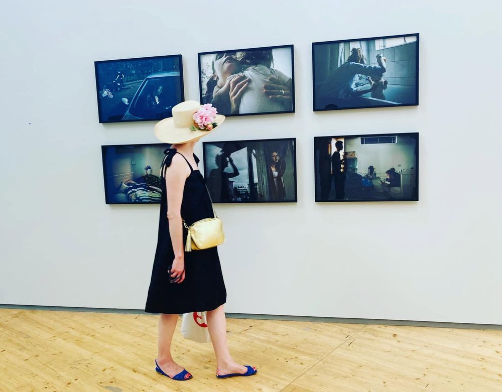 Une femme aux sandales brides passe devant une série de photos aux Rencontres de la photographie d'Arles de 2023.